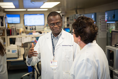 Dr. Fadeyi talking with another physician in the blood lab. 